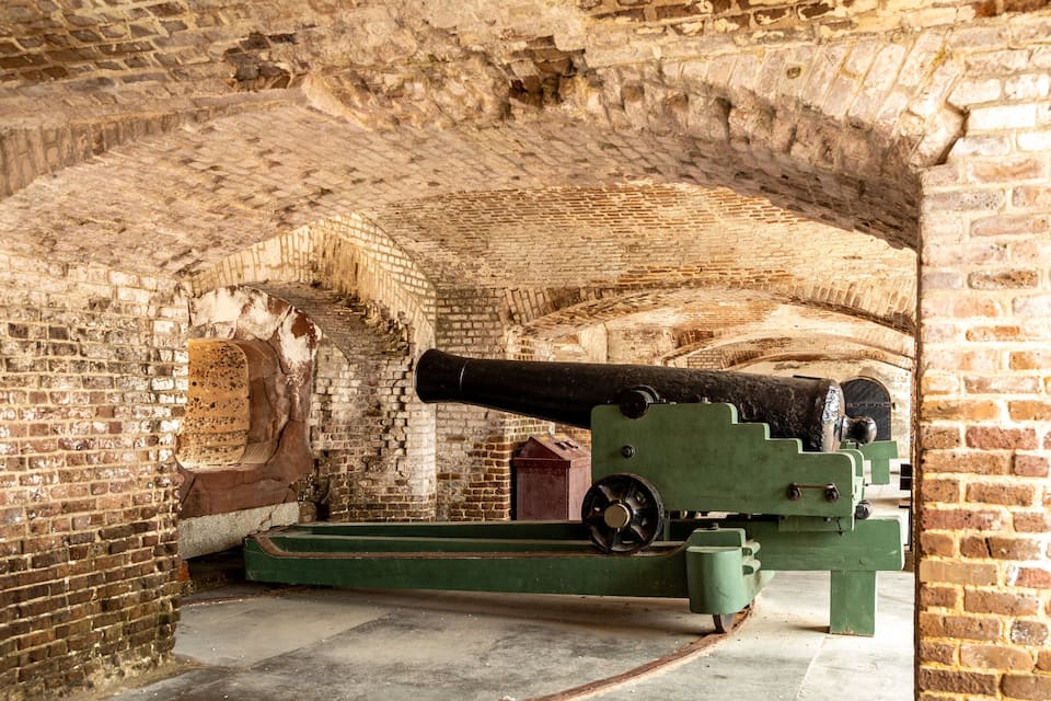 A historic cannon in a brick archway.