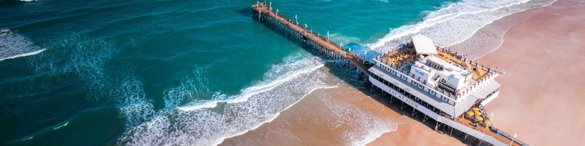 A pier extending into the ocean with a cruise ship docked at the end.