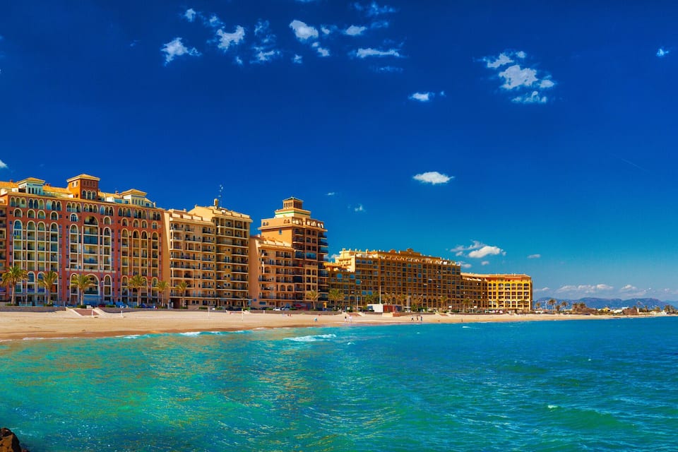 A beachfront hotel with a clear blue sky and turquoise waters.