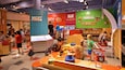 A colorful indoor play area with sections labeled 'MEAT' and 'LOCAL PRODUCE'.