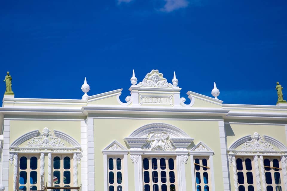 Ein prachtvolles Gebäude mit aufwendiger weißer Dekoration, Statuen und einem strahlend blauen Himmel im Hintergrund.