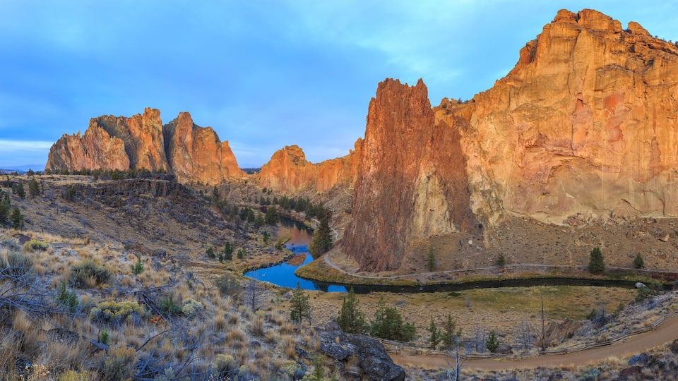 A canyon with a river, rocky cliffs, and sparse vegetation.
