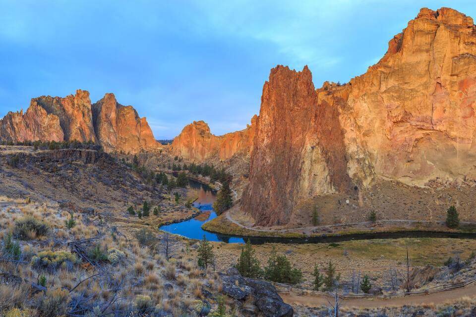 A canyon with a river, rocky cliffs, and sparse vegetation.