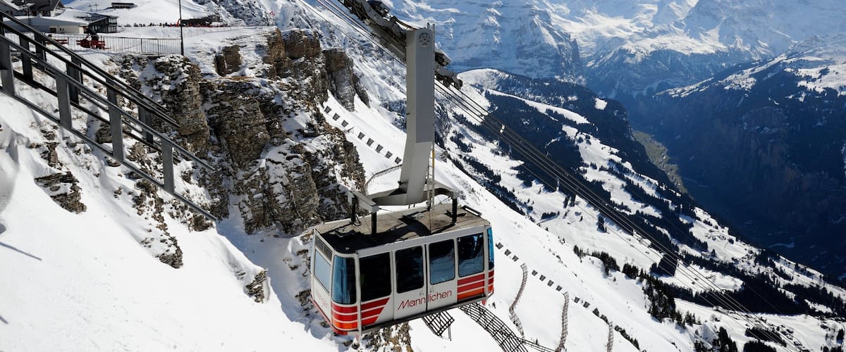 A cable car on a snowy mountain with a clear view of the surrounding peaks.