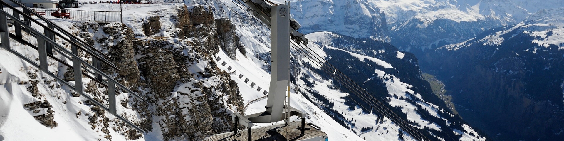 A cable car on a snowy mountain with a clear view of the surrounding peaks.