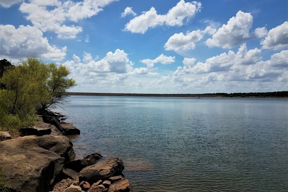 A calm lake with clear skies and scattered clouds.