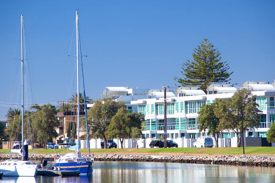 A marina with boats, a modern building, and a clear blue sky.