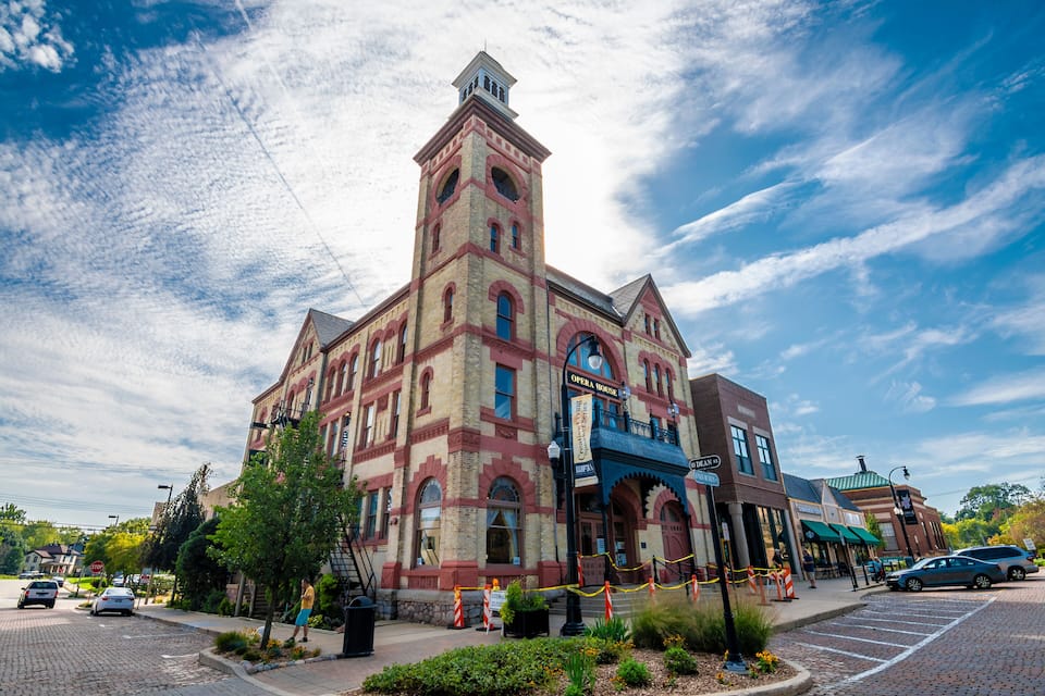 A historic building with a clock tower, a theater, and a street with cars and pedestrians.