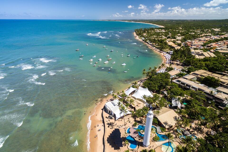 A coastal resort with clear turquoise waters, a sandy beach, and a white tower.