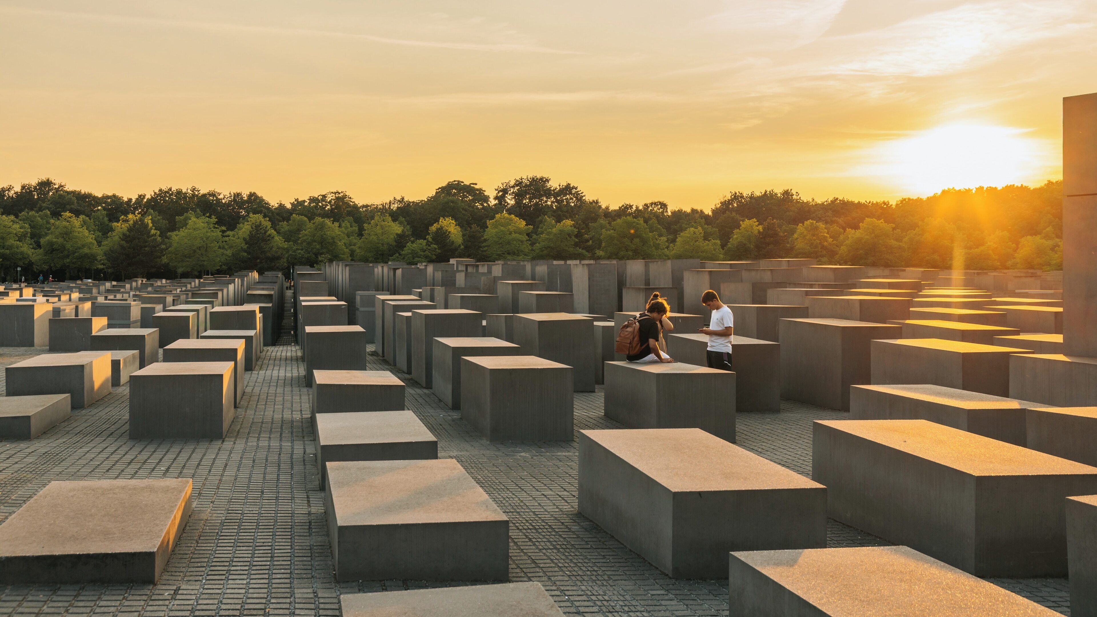 Holocaust Memorial in Berlin at sunset showcasing unique architecture and visitors reflecting on history