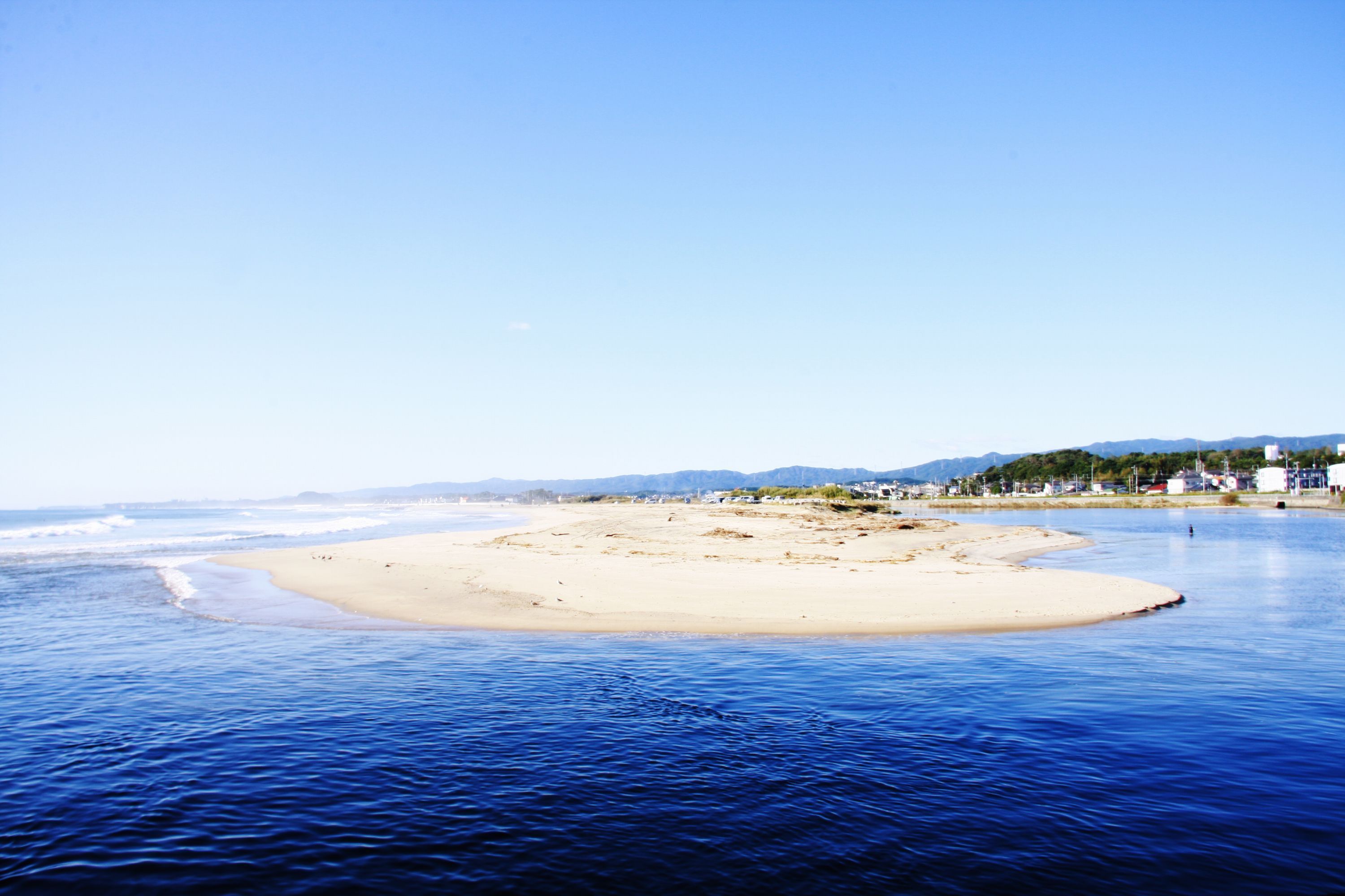A beach with clear blue water and a sandy shore.
