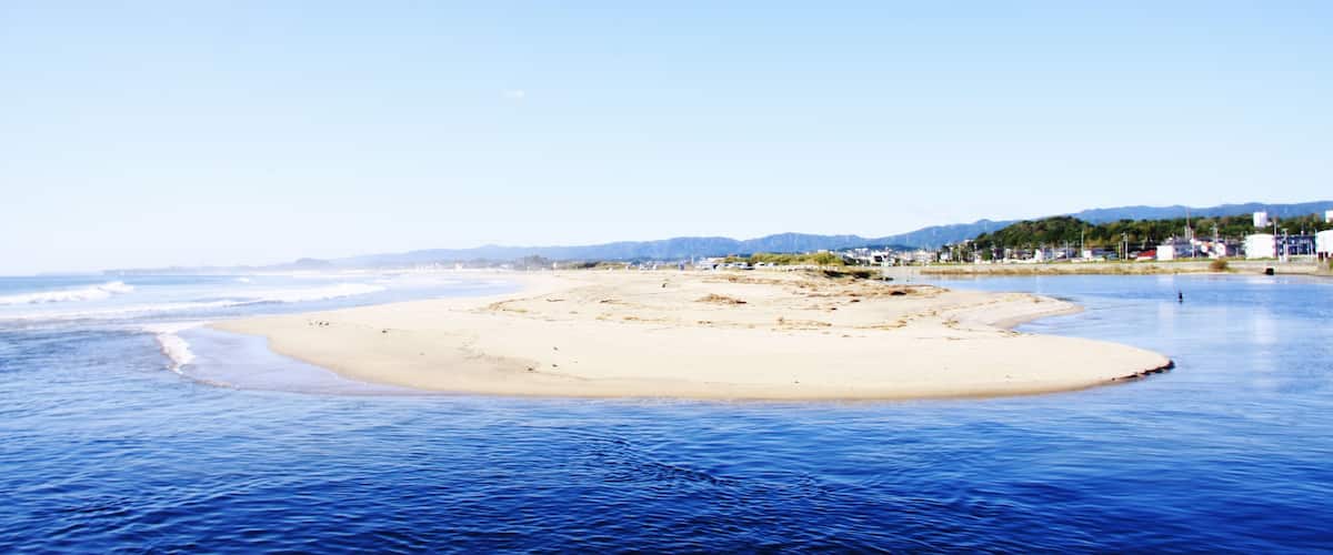 A beach with clear blue water and a sandy shore.