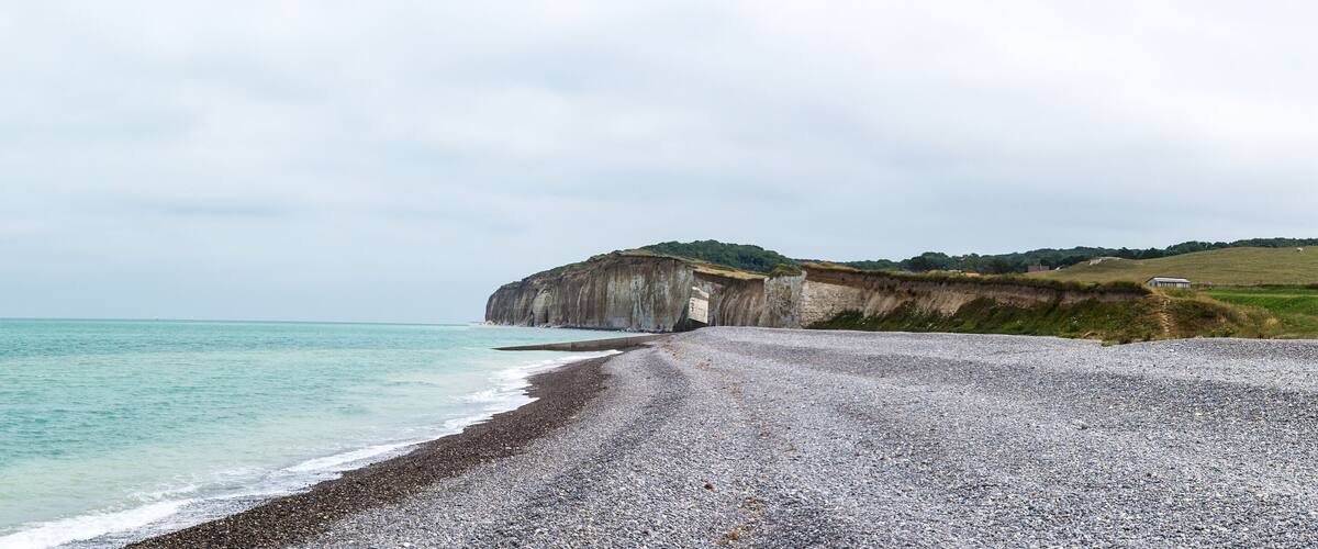A pebble beach with a cliff and ocean.