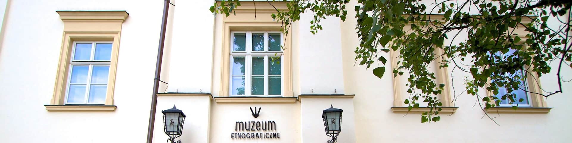 A museum entrance with a sign reading "museum etnograficzne" and a poster advertising an event from 17.05 to 29.09.2013.