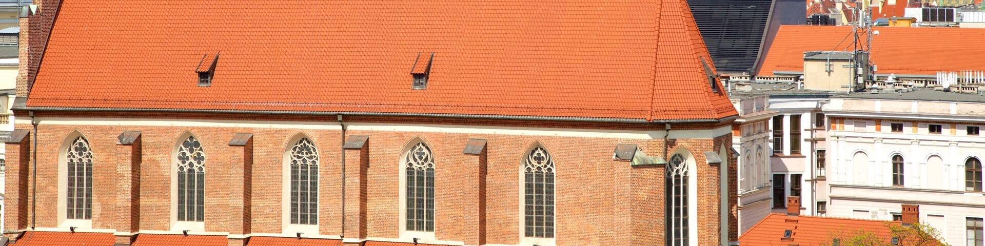 A church with a red roof and a cross on top, surrounded by other buildings.
