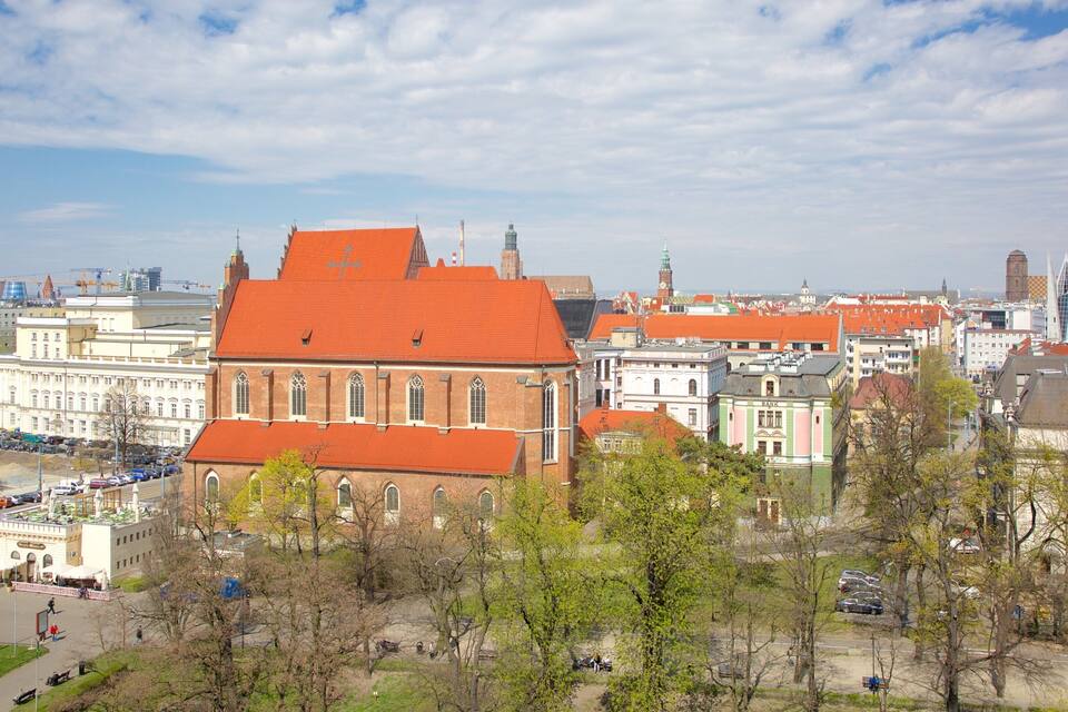 A cityscape with a prominent red-roofed building, a mix of historical and modern architecture, and a clear sky.