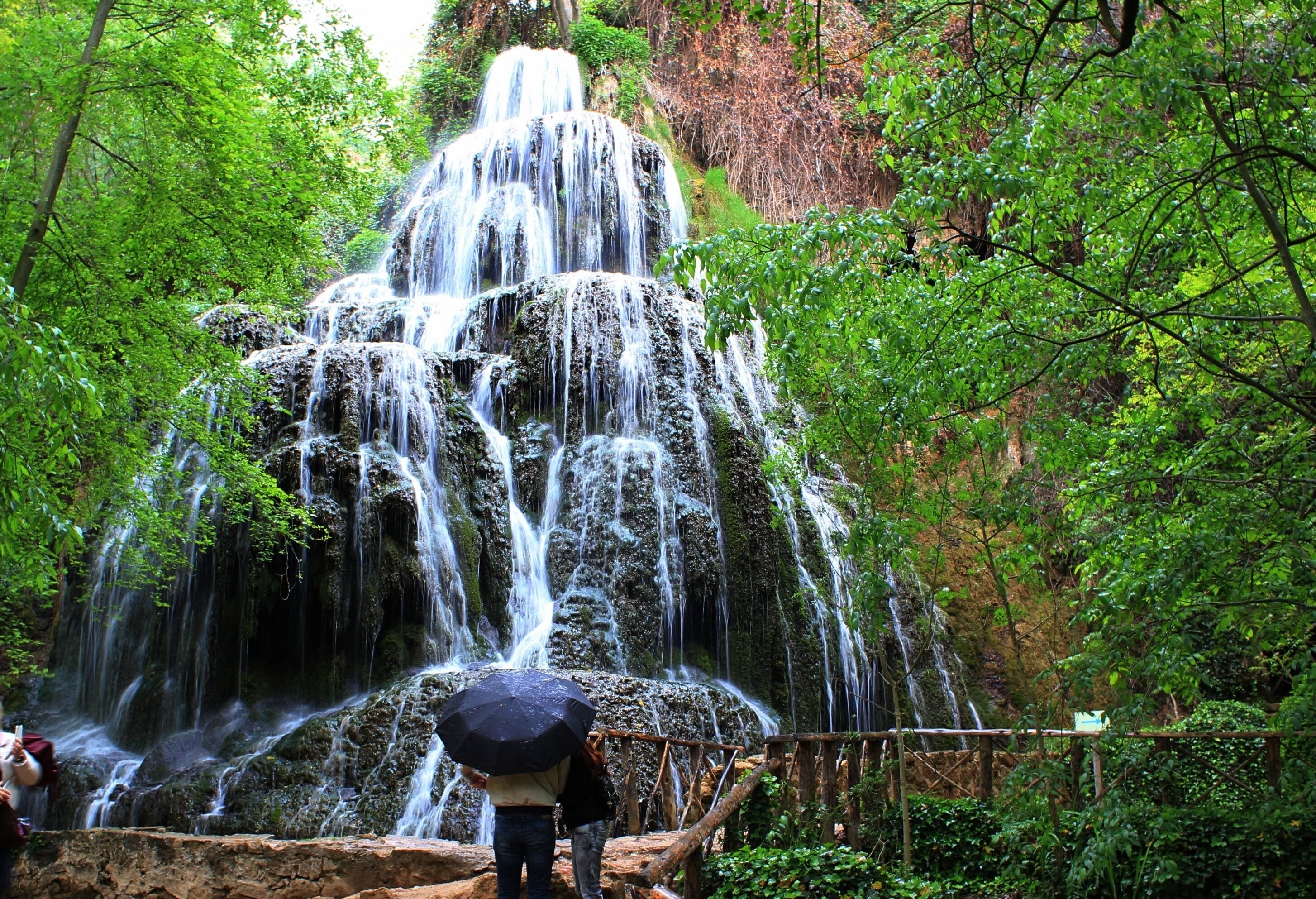 A multi-tiered waterfall surrounded by lush greenery.