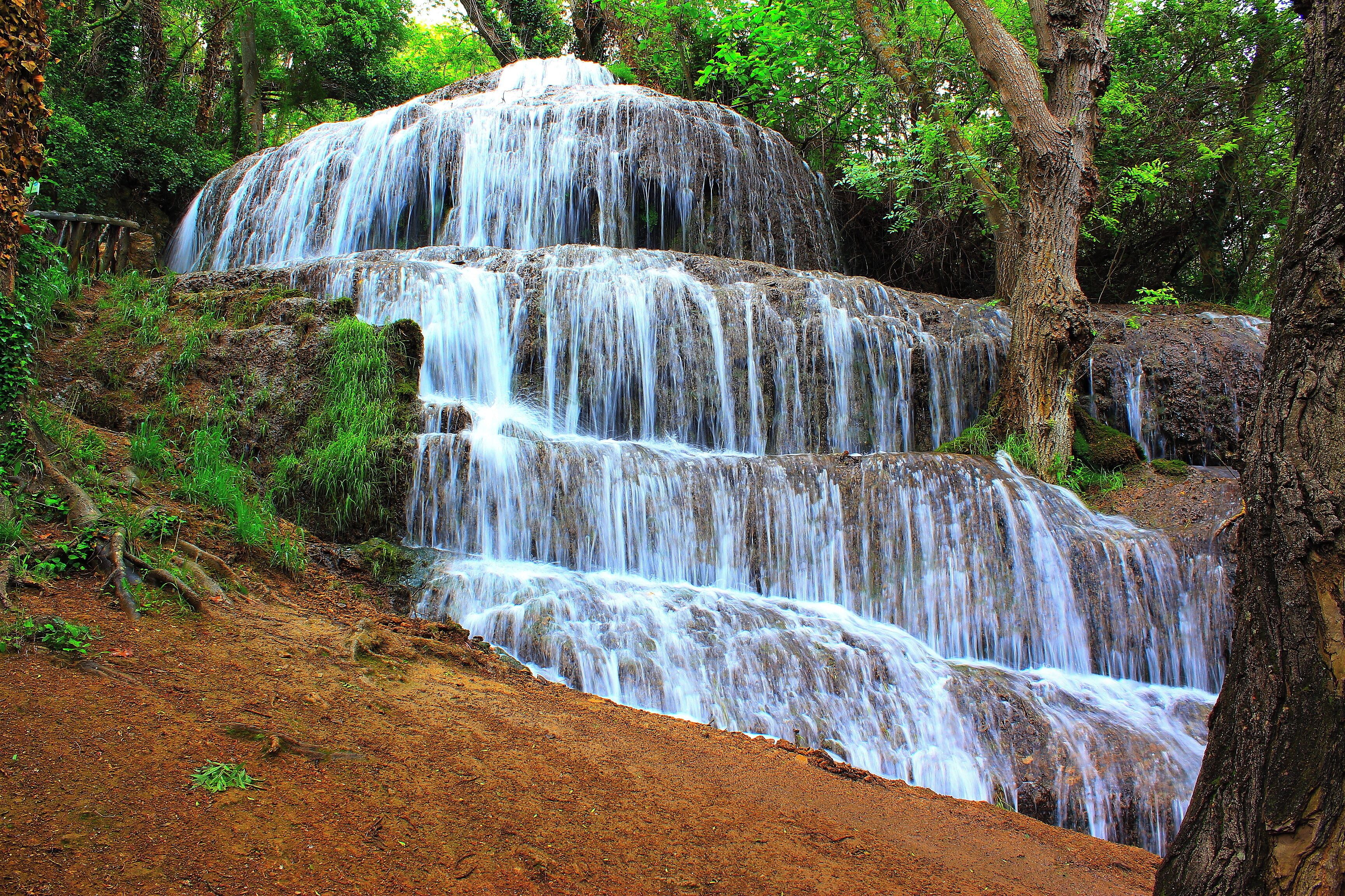 A multi-tiered waterfall surrounded by lush greenery.