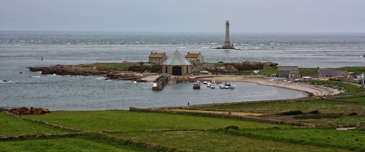 A coastal town with a lighthouse, a bridge, and boats in the harbor.