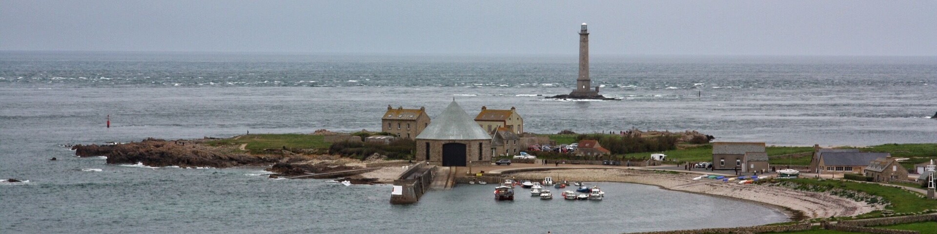 A coastal town with a lighthouse, a bridge, and boats in the harbor.