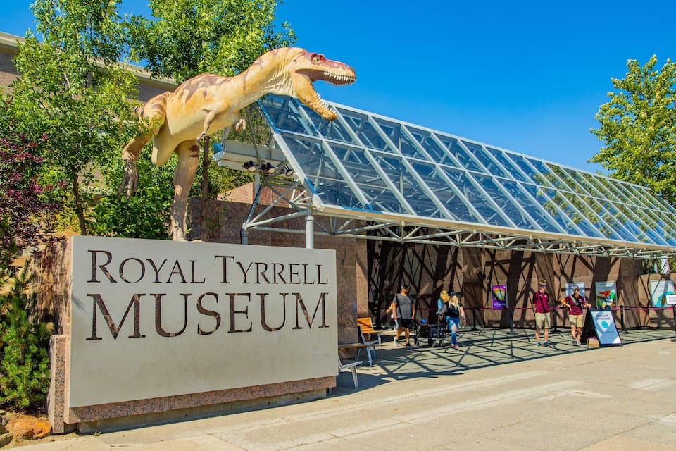 Entrada al Museo Real Tyrrell, con una estatua de dinosaurio y una estructura de techo de vidrio.