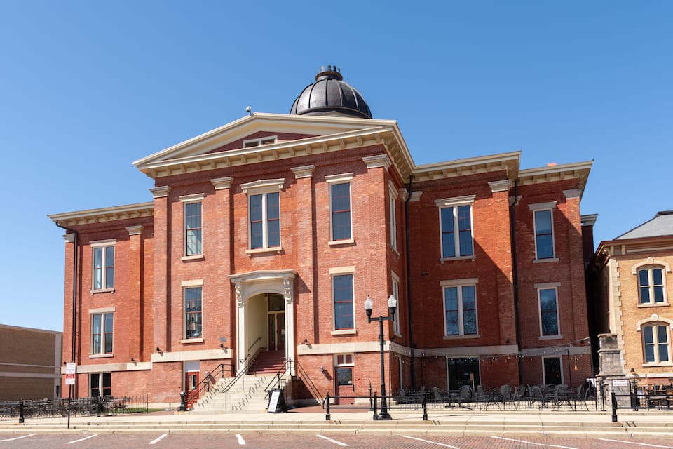 A large red brick building with a prominent dome and a staircase leading to the entrance.