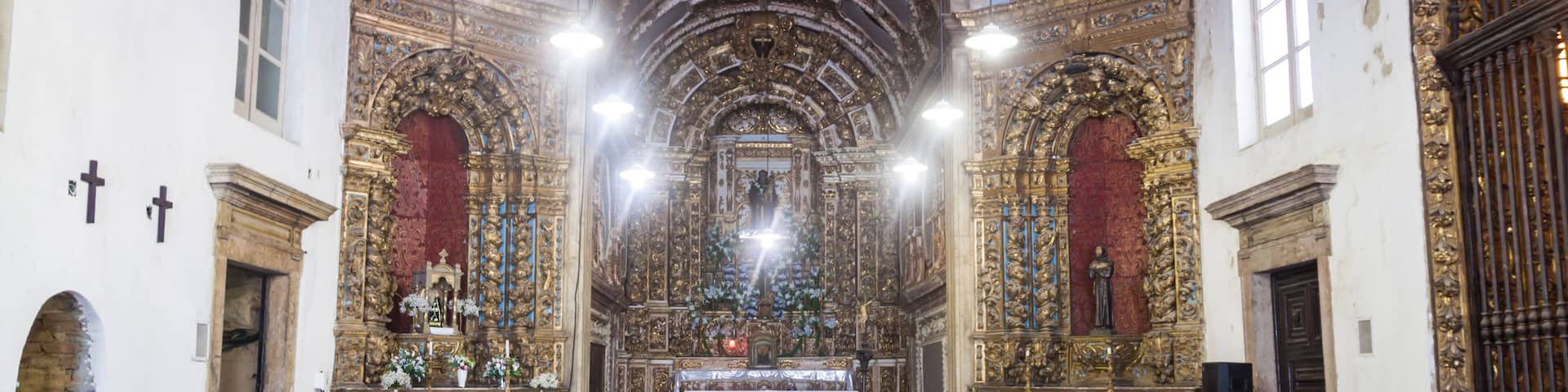 An ornate church interior with wooden pews, a central altar, and intricate gold decorations.
