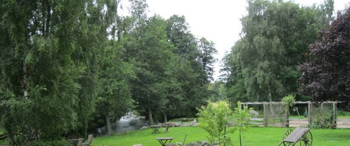 A grassy backyard with a pond, wooden deck, and outdoor furniture.