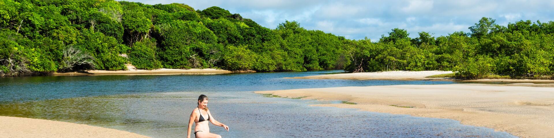 A woman, in the River, kicks water into the air.