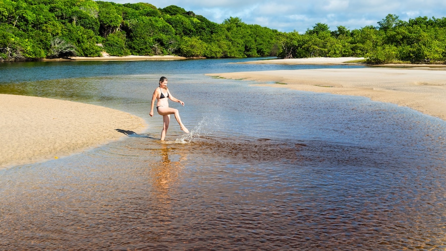 A woman, in the River, kicks water into the air.