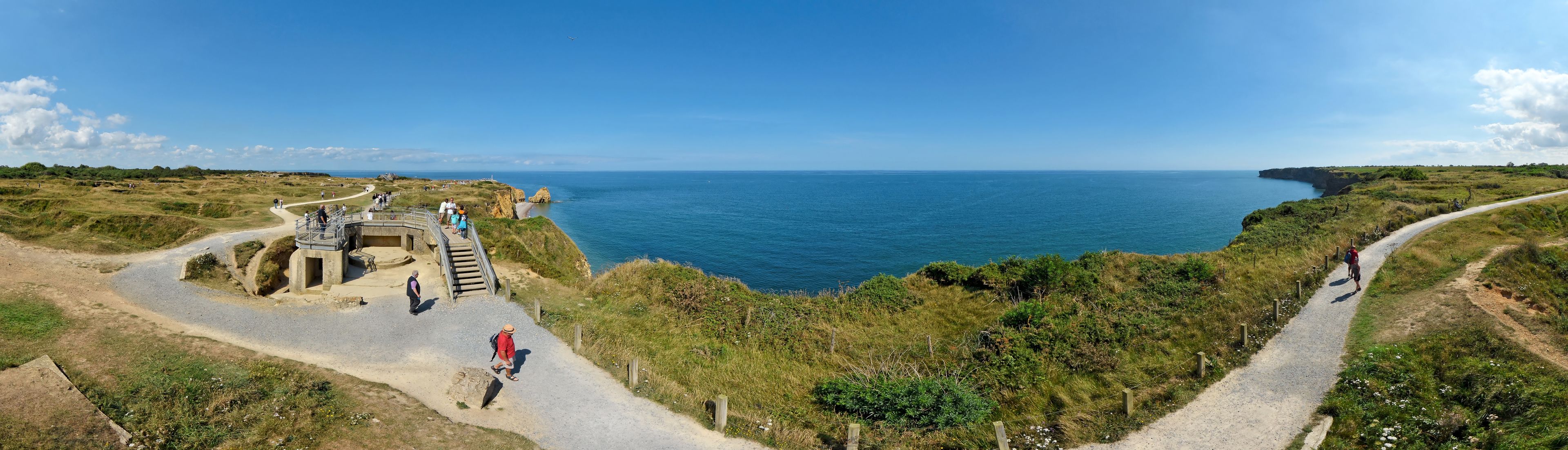 Un paysage côtier avec une promenade dallée, une plateforme d’observation et l’océan en arrière-plan.