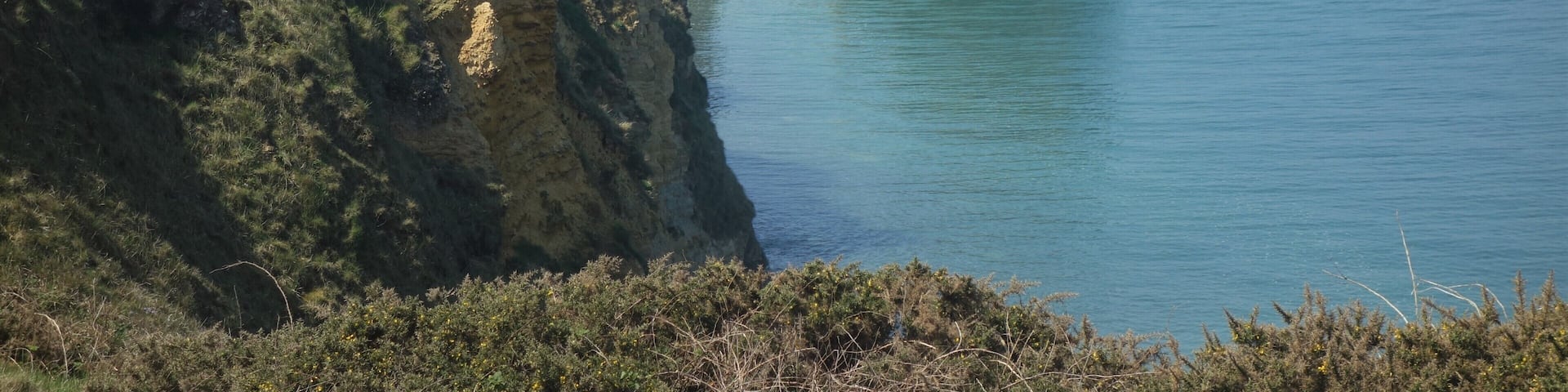 A coastal landscape with cliffs and a clear blue sea.