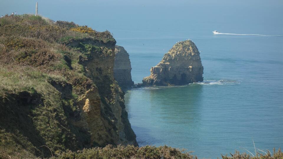 A coastal landscape with cliffs and a clear blue sea.