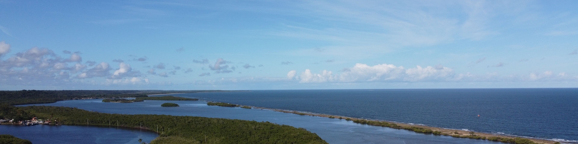 A coastal landscape with a large island surrounded by water, a clear sky, and a distant shoreline.