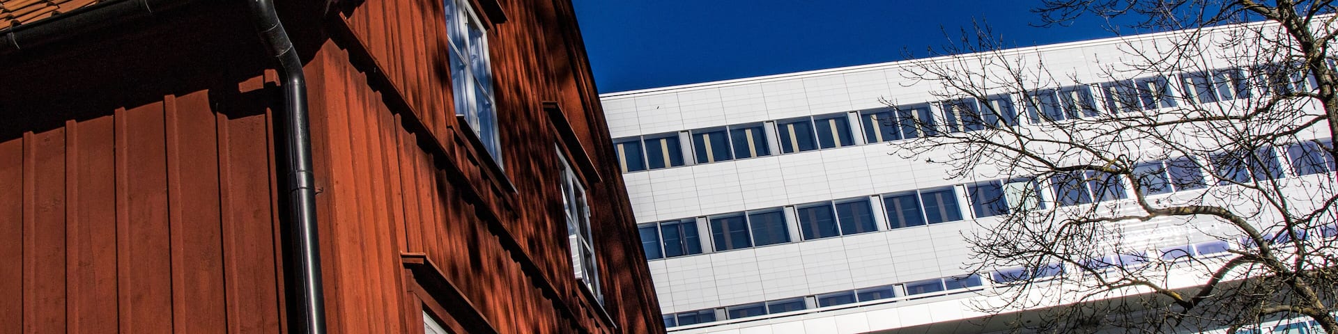 Stockholm, Sweden Oct 22, 2021 A red house contrast with the modern facade of the Karolinska Hospital.