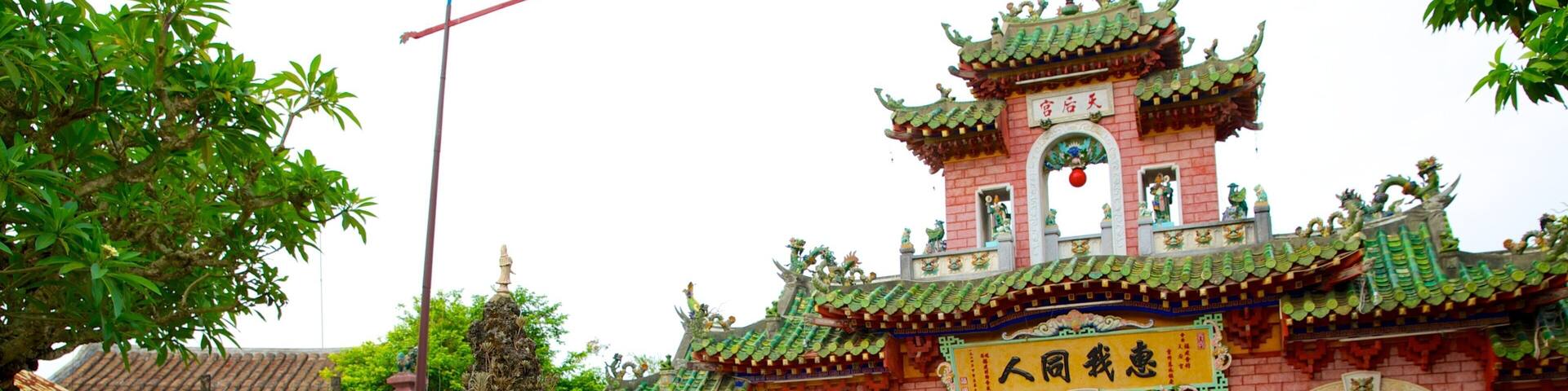 A traditional Chinese temple with ornate architecture, a large rock garden, and various potted plants.