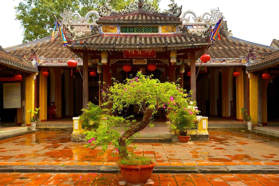 A traditional Chinese building with ornate architecture, a central tree, and red lanterns.