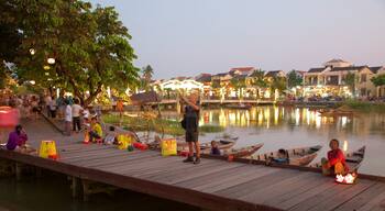 A wooden dock with people, boats, and a river.