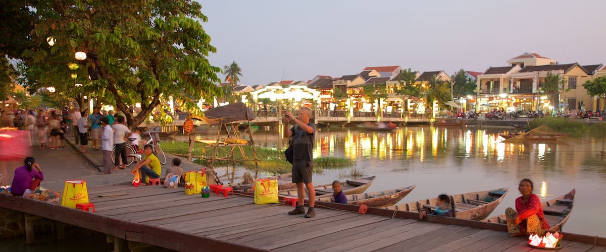 A wooden dock with people, boats, and a river.