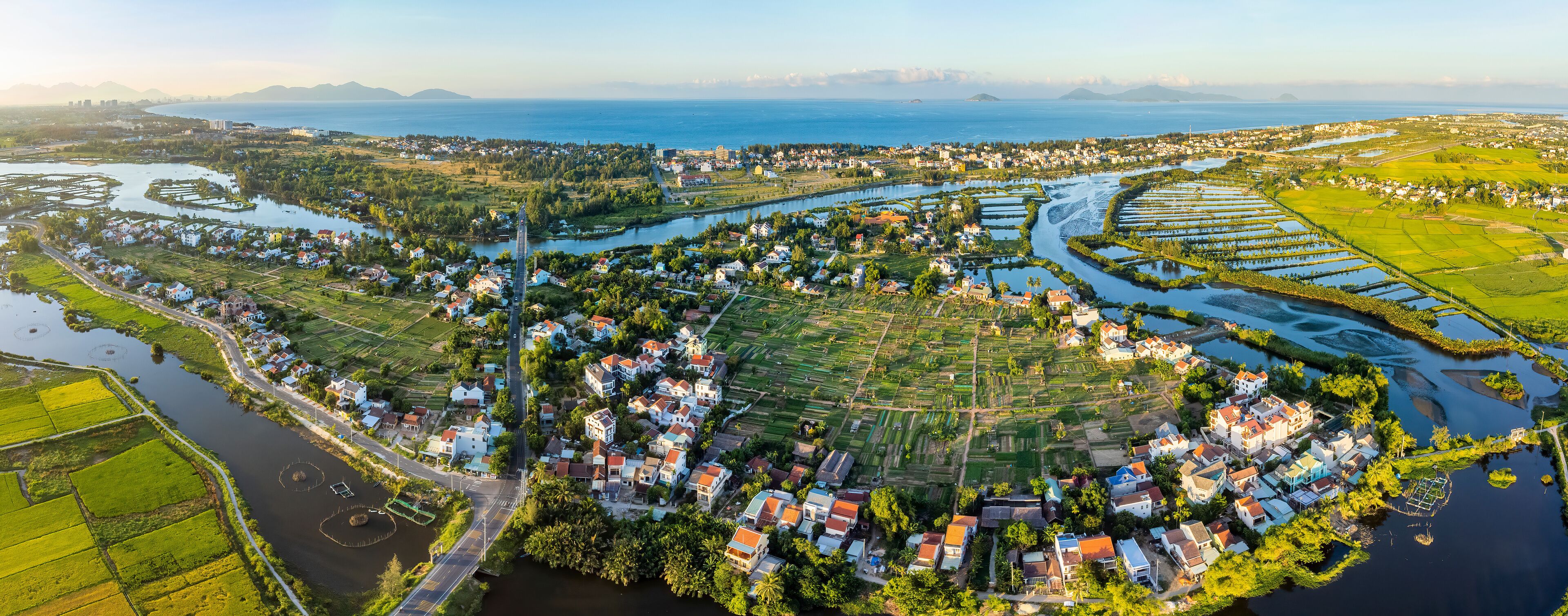 An aerial view of a coastal town with a river, farmland, and residential areas.