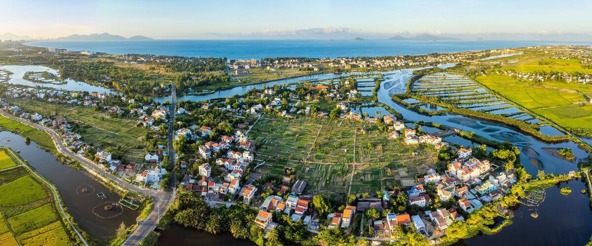 An aerial view of a coastal town with a river, farmland, and residential areas.