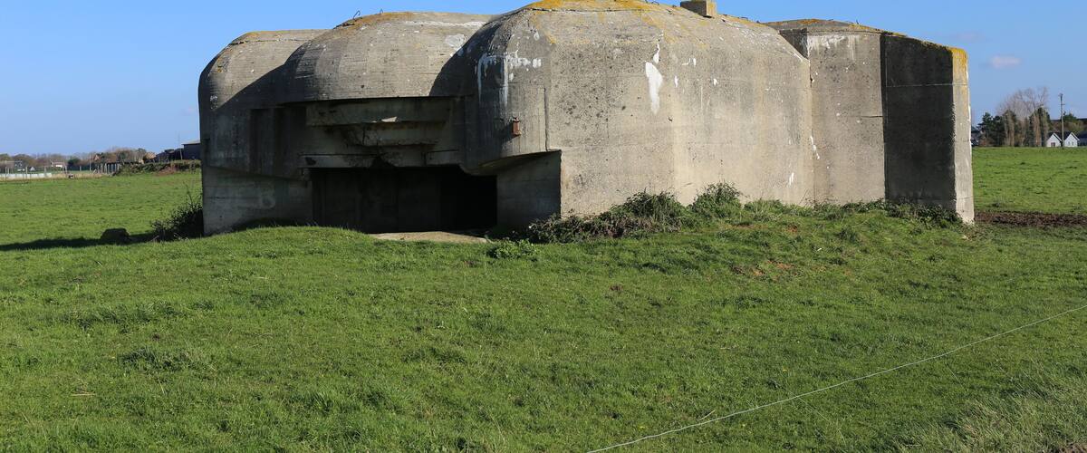 A concrete bunker in a grassy field.
