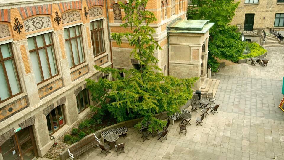 A courtyard with a brick building, a tree with green leaves, and outdoor furniture.