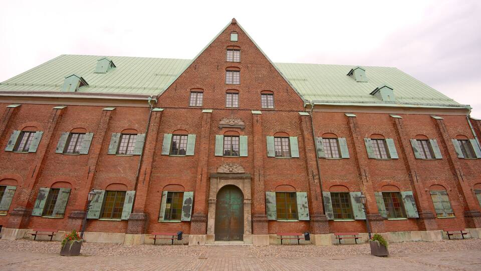 A large red brick building with green shutters and a green roof.