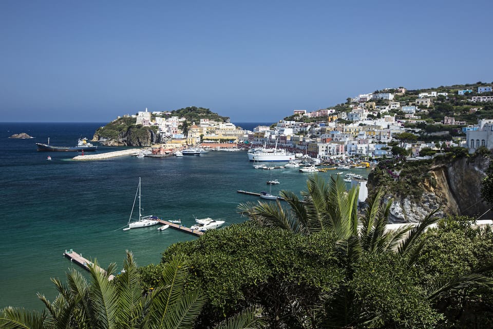 A coastal town with a harbor, boats, and buildings on a hillside.