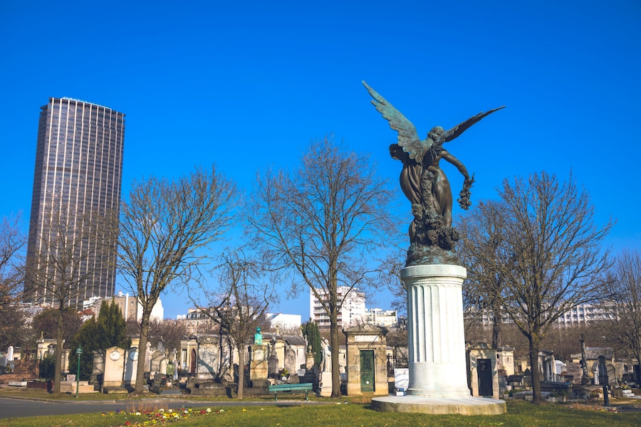 A statue of an angel with outstretched wings, a tall modern building, and a cemetery with tombstones.