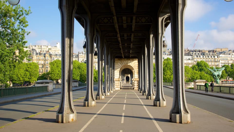 Uma ponte para pedestres com colunas de metal ornamentadas e uma passagem em arco.