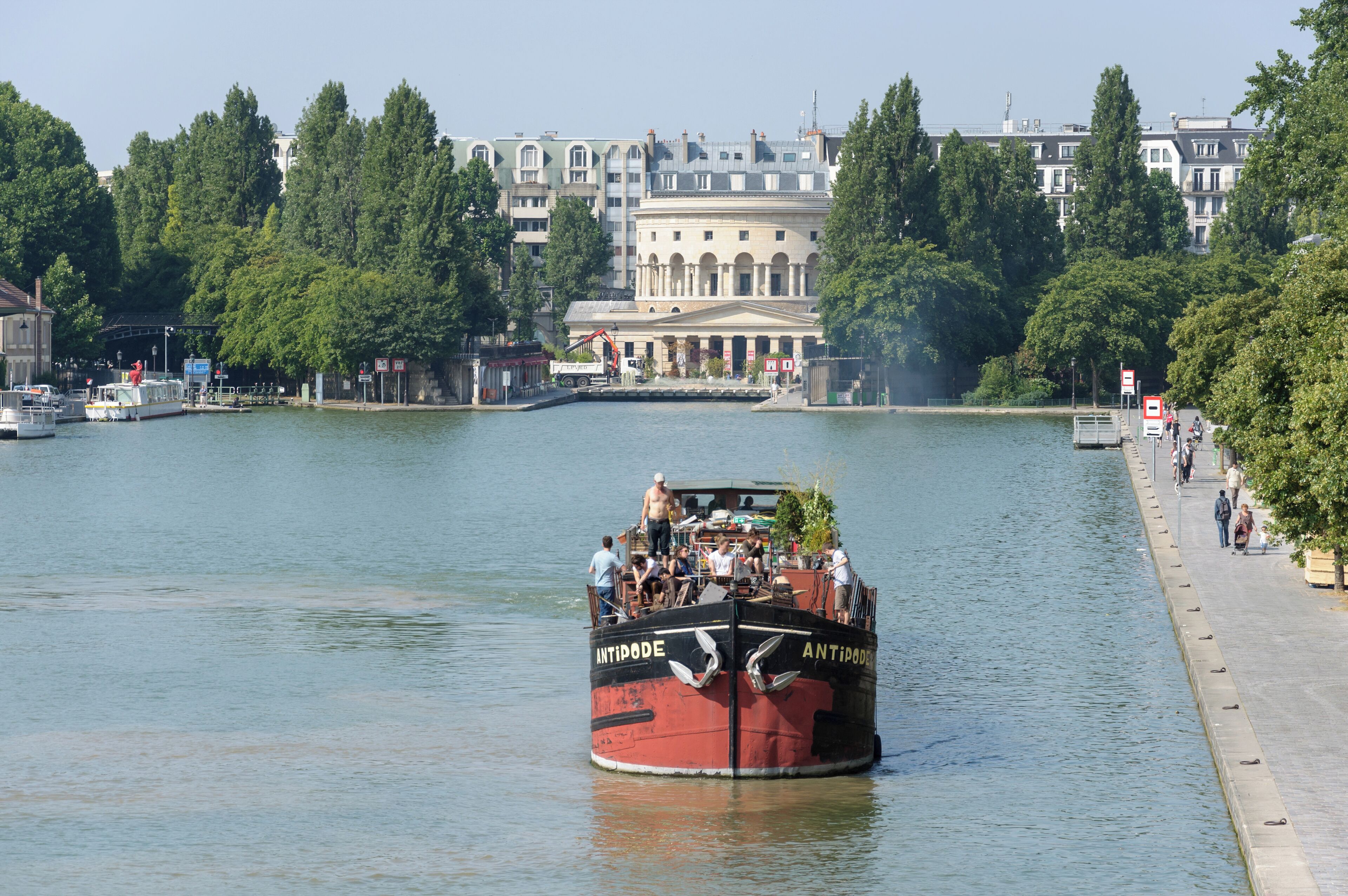 Barge in the bassin de la Villette with the Rotonde de la Villette in the background, in Paris, France.