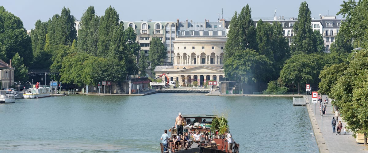 Barge in the bassin de la Villette with the Rotonde de la Villette in the background, in Paris, France.