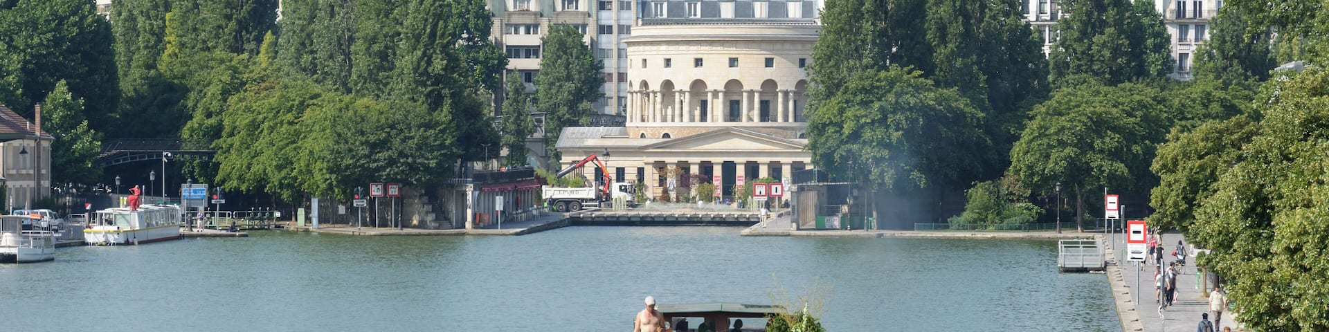 Barge in the bassin de la Villette with the Rotonde de la Villette in the background, in Paris, France.